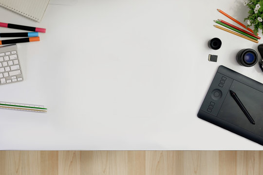 Creative professional designer's desk from above. Designer workspace top view with essential elements on white table.