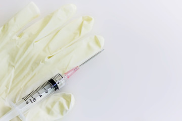 Glove and syringe on white table.