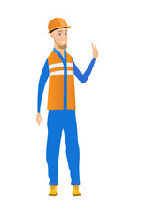 Young caucasian builder showing victory gesture.