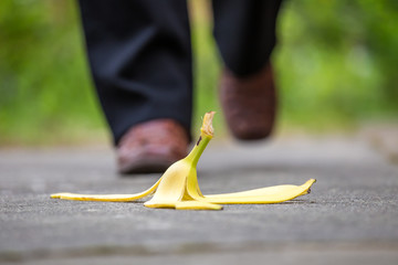 eine Bananenschale liegt auf der Strasse und ein Mann läuft darauf zu