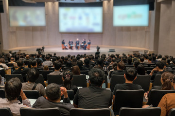 Rear view of Audience over the speakers on the stage in the conference hall or seminar meeting,...