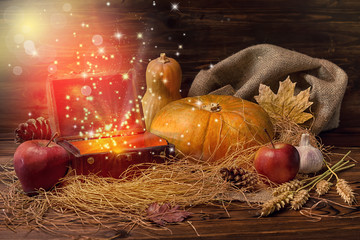 thanksgiving concept of pumpkins, apple, garlic, straw and opened chest treasure with mystical...