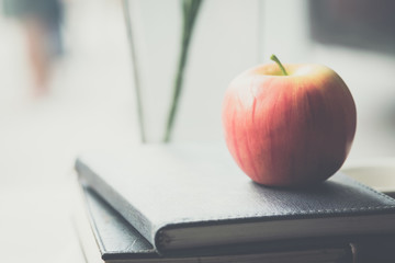Apples placed on books and notebooks in the morning light.The image is blurred and Soft focus.
