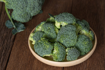 Bunch of fresh green broccoli on wood plate.
