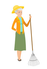 Senior caucasian farmer holding gardening rake.