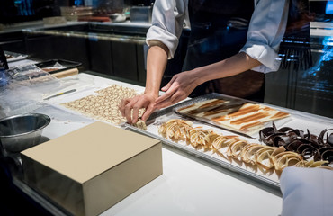 Pastry chef hands working on chocolate garnishes for chocolate decoration on tray