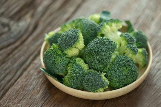 Fresh green broccoli on wood plate. Selective focus.