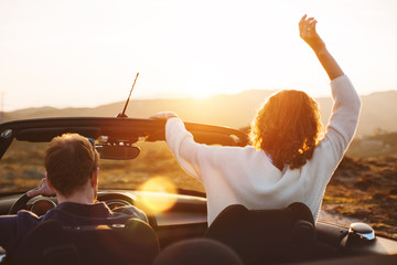 A young couple enjoying the sunset in a convertible