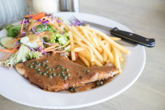 Pork chops steak with salad and french fries.