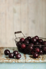 Ripe plums in a basket on a wooden background.