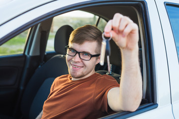 Naklejka premium Excited young man showing a car key inside his new vehicle