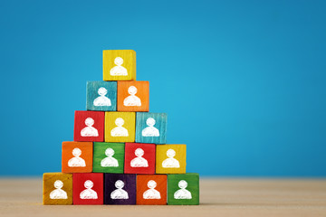 image of a wood blocks pyramid with people icons over wooden table, human resources and management...