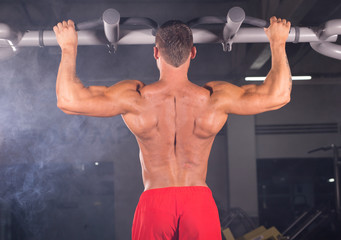 A young man doing pull ups in the Gym.