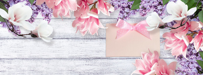 Obraz na płótnie Canvas Magnolia, lilac flowers and card on shabby board