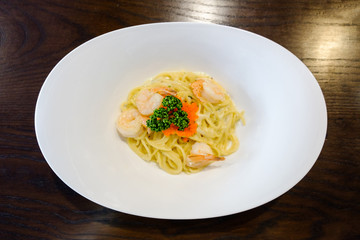 delicious spaghetti with shrimps and tobiko on a plate on a wooden background