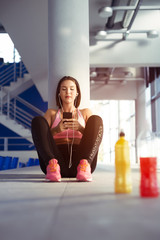 Young woman with earphones listening to music after hard workout