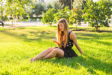 Young beautiful woman enjoying music outdoors on a grass