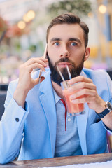 Stylish bearded male in a blue jacket using smartphone.