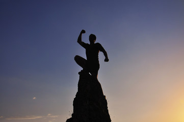 Man raised hand on top of the mountain to celebrate success. Men on the top of the steep rock 