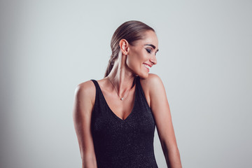 Beautiful woman in black night fashion dress posing on a gray background.