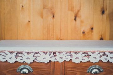 old dresser with embroidered tablecloth, wooden background