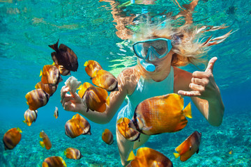 Happy family - girl in snorkeling mask dive underwater with tropical fishes in coral reef sea pool. Travel lifestyle, water sport outdoor adventure, swimming lessons on summer beach holiday with kids