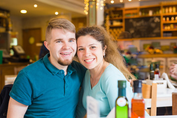 Portrait of beautiful young couple in love at a coffee shop. Gorgeous smiling girl and her boyfriend is laughing