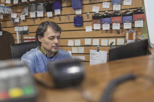 Owner sitting at checkout counter at store