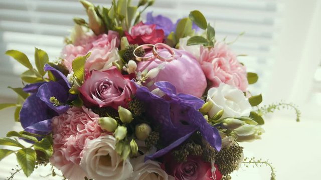 Golden rings on colourful wedding bouquet