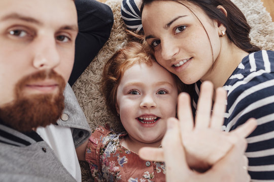 High angle portrait of smiling family lying on carpet at home