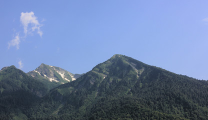 Green mountain tops against a blue sky.