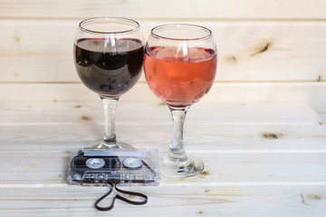 Glasses of red wine , rose and cassette tape isolated on a wooden  background. Romantic date concept 