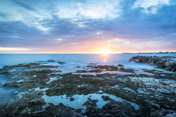 Obraz premium Tropical sunset with ocean and corals on foreground