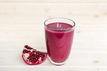 A glass of ripe pomegranate juice on wooden background. Healthy living concept.