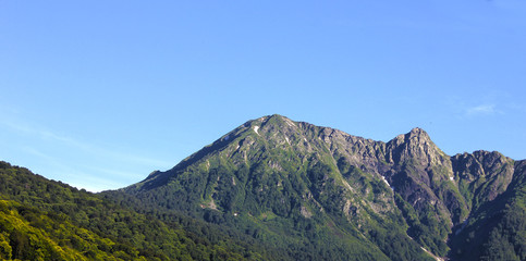 Obraz premium Mountain landscape. Green mountain with a rocky peak against the blue sky.