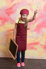 Small girl cook in hat with blackboard.