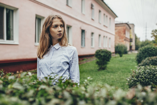 Thoughtful teenage girl standing by plants against building