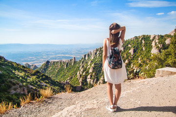 Young woman with backpack enjoying the view in Montserrat mountain on a hot summer day