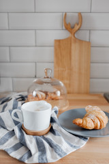 A cup of coffee and a croissant on the table. 