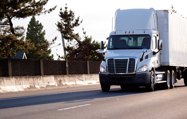 White modern semi truck with container for cargo carriers on the road
