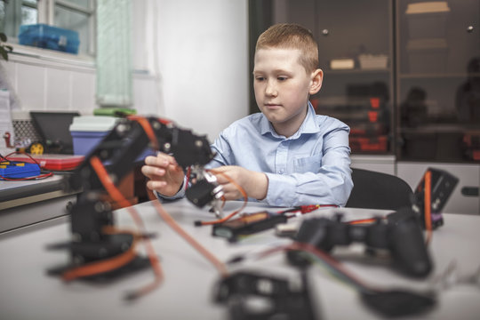 Boy operating machinery at table in classroom