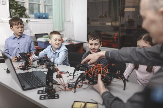 Teacher showing machinery to students sat table in classroom