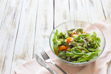 Warm vegetable salad with pumpkin, pearl barley and spinach on old wooden white background.
