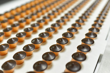 Fliessband mit Nougat Pralinen bei der Herstellung in einer Lebensmittelfabrik für Süßigkeiten // Flowing ribbon with nougat chocolates in the making in a food factory for sweets