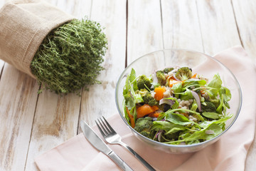 Warm vegetable salad with pumpkin, pearl barley and spinach on old wooden white background.
