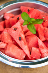 Red sweet watermelon pieces in a bowl, garnished with fresh mint