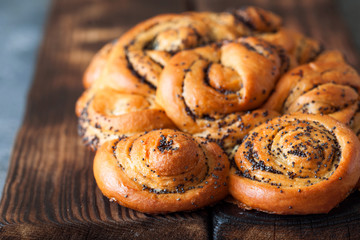 Rolled braided pie with poppy seeds on rustic board close up
