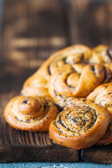 Rolled braided pie with poppy seeds on rustic board close up