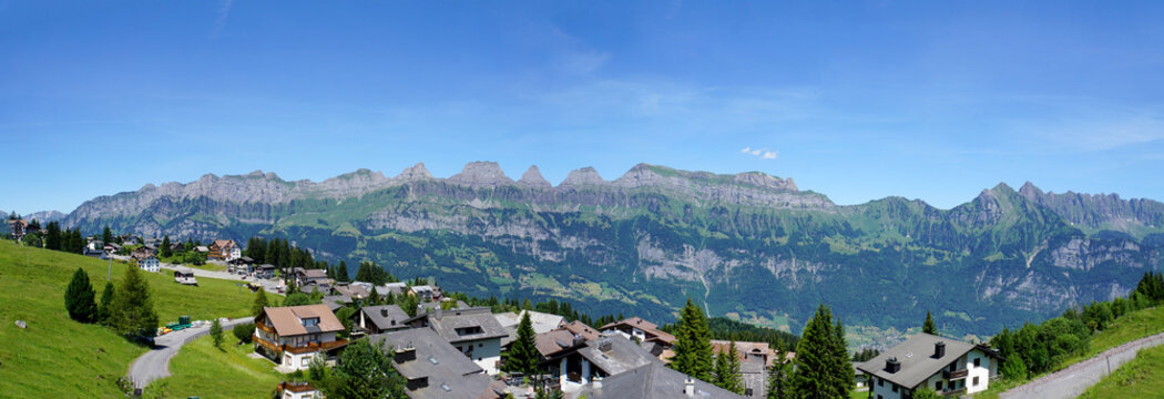 Panorama der Bergkette Churfirsten/ Die Bergkette der Churfirsten im Kanton St. Gallen in der Schweiz, im Vordergrund H&auml;user, Panoramabild 