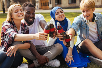 Enthusiastic optimistic friends clanging their bottles